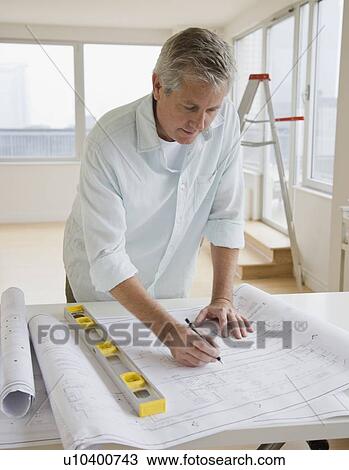 Stock Image - Man writing on blueprints. Fotosearch