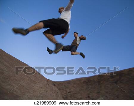 Men jumping over rock formations View Large Photo Image Stock Photo - Men jumping over rock formations. Fotosearch
