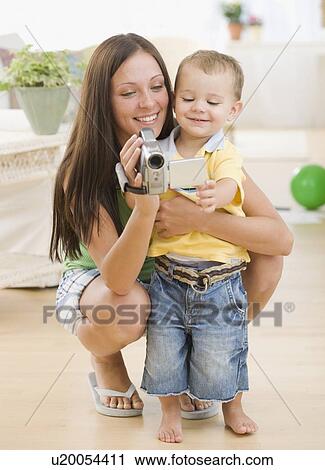 Stock Image - Mother and baby looking at video camera. Fotosearch