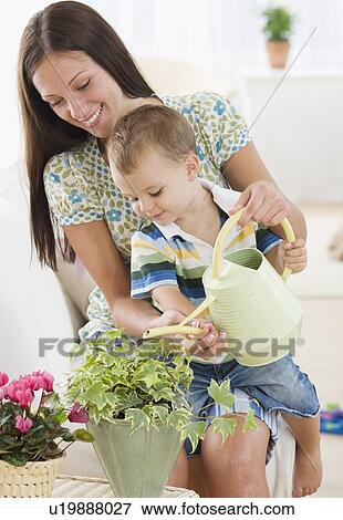 Stock Photo - Mother and baby watering potted plant. Fotosearch