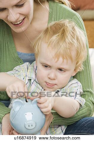 Mother and young son putting change in piggy bank View Large Photo Image Stock Photo - Mother and young son putting change in piggy bank. Fotosearch