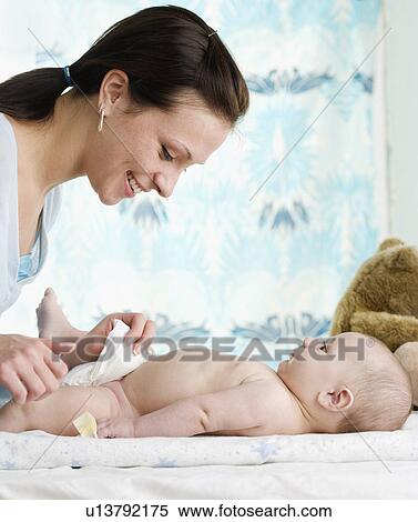 Mother changing baby’s diaper View Large Photo Image Stock Photography - Mother changing baby’s diaper. Fotosearch