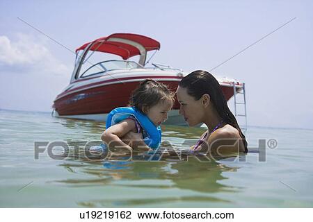 Mother helping daughter swim near boat, Florida, United States View Large Photo Image Stock Image - Mother helping daughter swim near boat, Florida, United States. Fotosearch