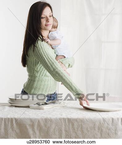 Mother holding baby and setting the table View Large Photo Image Stock Image - Mother holding baby and setting the table. Fotosearch