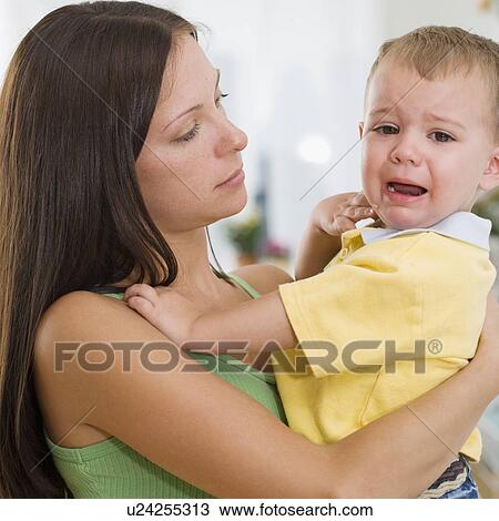Mother holding crying baby View Large Photo Image Stock Image - Mother holding crying baby. Fotosearch