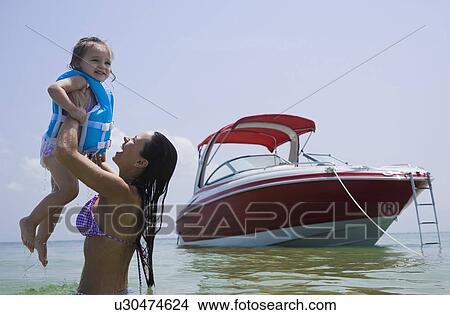 Picture - Mother holding up daughter in water, Florida, United States. Fotosearch