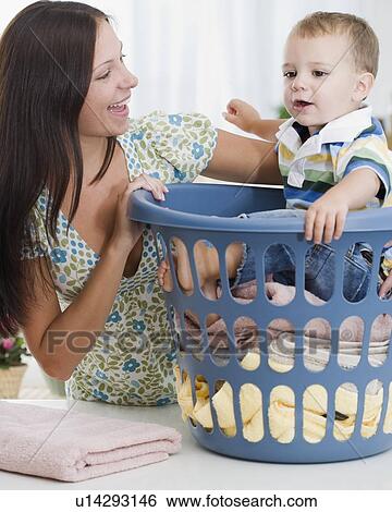 Mother smiling at baby in laundry basket View Large Photo Image Stock Photograph - Mother smiling at baby in laundry basket. Fotosearch
