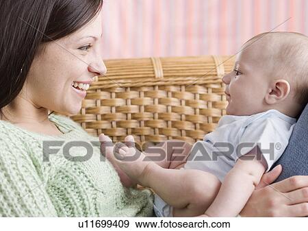 Stock Photo - Mother smiling at baby on her lap. Fotosearch