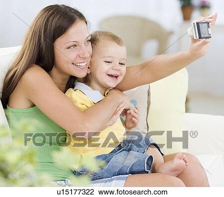 Stock Image - Mother taking own photograph with baby. Fotosearch