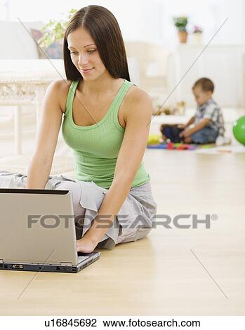 Mother using laptop while baby plays View Large Photo Image Stock Image - Mother using laptop while baby plays. Fotosearch