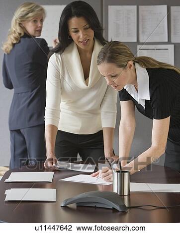 Multi-ethnic businesswomen looking at paperwork View Large Photo Image Stock Image - Multi-ethnic businesswomen looking at paperwork. Fotosearch