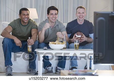 Stock Photo - Multi-ethnic men watching sports on television. Fotosearch