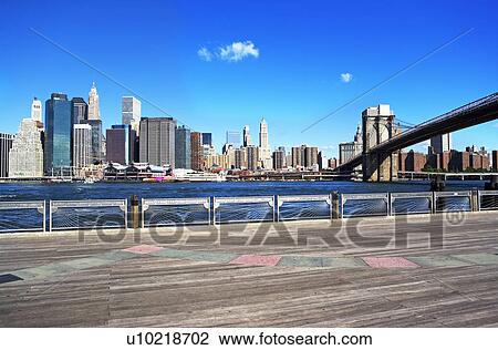 Stock Image - New York City skyline and Brooklyn bridge under blue sky. Fotosearch