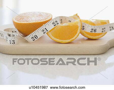 Orange halves and tape measure on cutting board View Large Photo Image Stock Photo - Orange halves and tape measure on cutting board. Fotosearch
