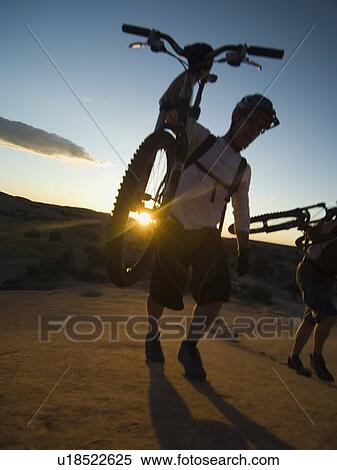 Stock Photography - People carrying mountain bikes. Fotosearch
