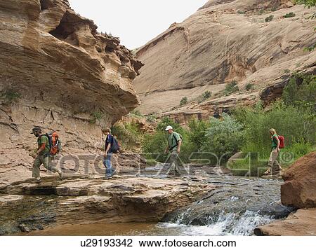 Stock Image - People hiking over stream. Fotosearch