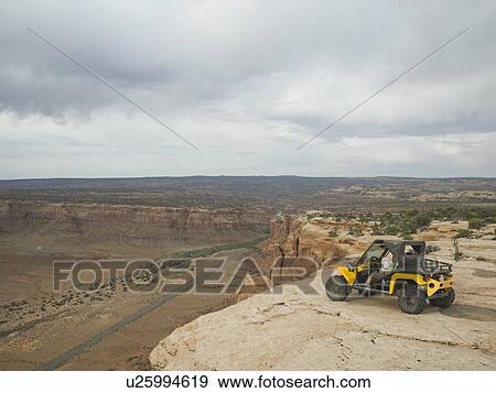 Stock Photo - People in off-road vehicle at edge of cliff. Fotosearch