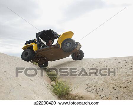 Stock Image - People in off-road vehicle on rock formation. Fotosearch