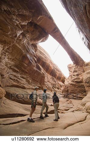 Stock Image - People looking up at rock formations. Fotosearch