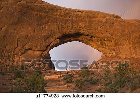 Stock Photo - People standing under rock formation. Fotosearch