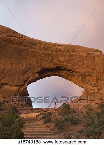 Stock Photo - People standing under rock formation. Fotosearch
