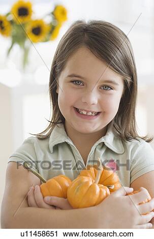 Stock Image - Portrait of girl holding pumpkins. Fotosearch