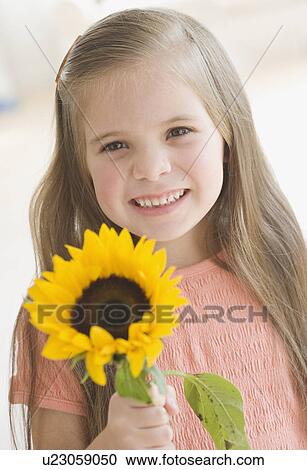 Stock Image - Portrait of girl holding sunflower. Fotosearch