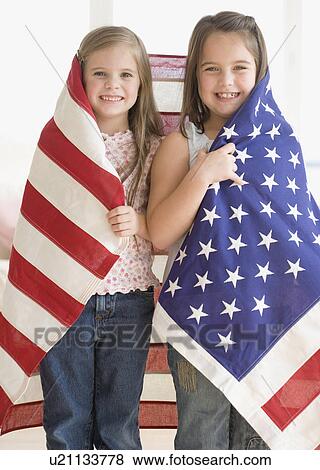 Stock Photo - Portrait of sisters wrapped in American flag. Fotosearch
