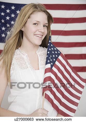 Stock Image - Portrait of teenage girl holding American flag. Fotosearch