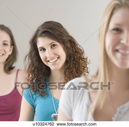 Stock Image - Portrait of teenage girl next to friends. Fotosearch