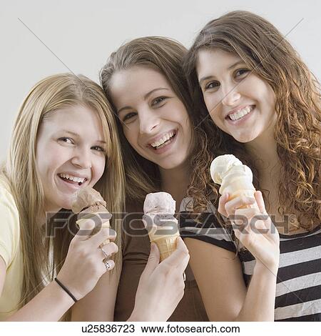 Stock Image - Portrait of teenage girls eating ice cream cones. Fotosearch