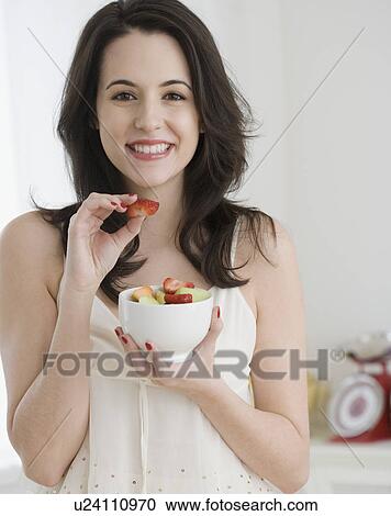 Stock Image - Portrait of woman eating fruit salad. Fotosearch