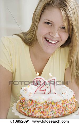 Stock Image - Portrait of woman with Twenty First birthday cake. Fotosearch