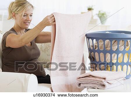 Pregnant woman folding laundry View Large Photo Image Picture - Pregnant woman folding laundry. Fotosearch