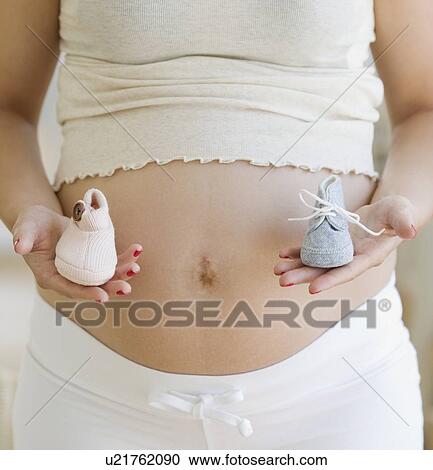 Pregnant woman holding boy and girl shoes View Large Photo Image Stock Image - Pregnant woman holding boy and girl shoes. Fotosearch