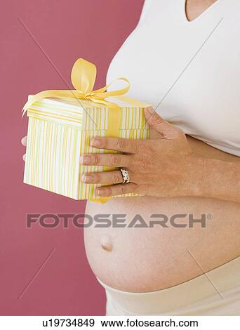 Stock Photo - Pregnant woman holding gift. Fotosearch