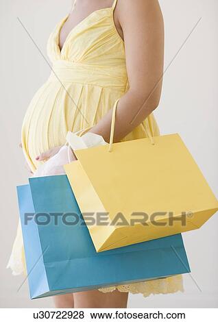 Pregnant woman holding shopping bags View Large Photo Image Stock Photo - Pregnant woman holding shopping bags. Fotosearch