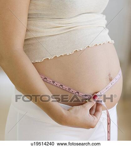 Pregnant woman measuring belly View Large Photo Image Stock Image - Pregnant woman measuring belly. Fotosearch