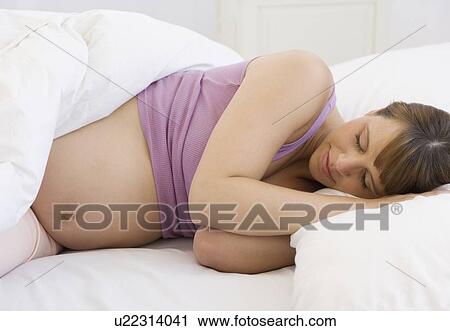 Stock Image - Pregnant woman sleeping in bed. Fotosearch