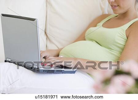 Stock Image - Pregnant woman typing on laptop. Fotosearch