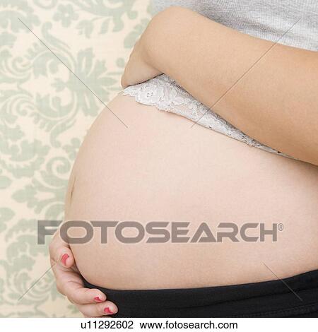 Stock Image - Pregnant woman with hands on belly. Fotosearch