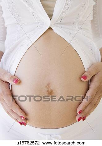 Stock Image - Pregnant woman with hands on belly. Fotosearch
