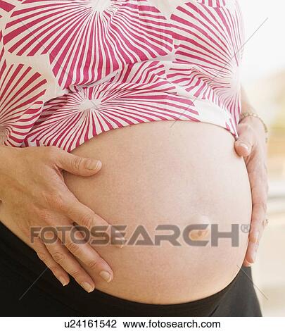 Stock Image - Pregnant woman with hands on belly. Fotosearch