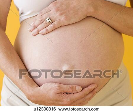 Stock Photograph - Pregnant woman with hands on belly. Fotosearch