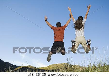 Rear view of couple jumping, Utah, United States View Large Photo Image Stock Photography - Rear view of couple jumping, Utah, United States. Fotosearch