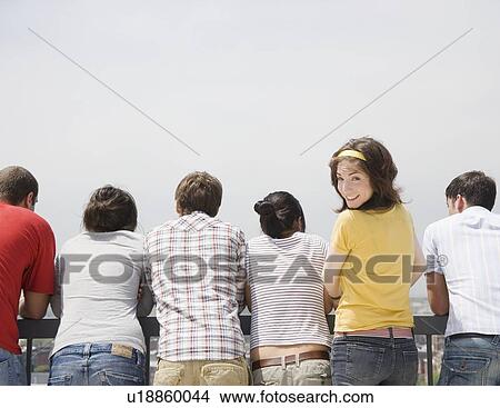 Rear view of friends with woman looking over shoulder View Large Photo Image Picture - Rear view of friends with woman looking over shoulder. Fotosearch