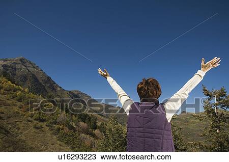 Stock Image - Rear view of woman with arms raised, Utah, United States. Fotosearch