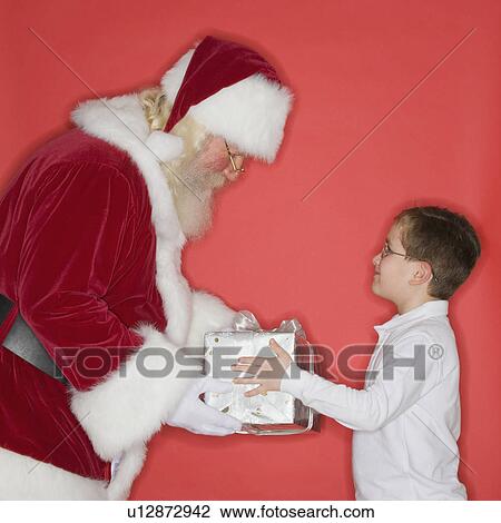 Stock Image - Santa Claus handing gift to boy. Fotosearch
