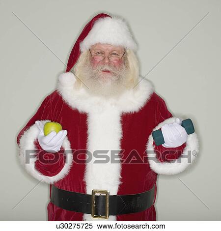 Stock Photography - Santa Claus holding apple and dumbbell. Fotosearch
