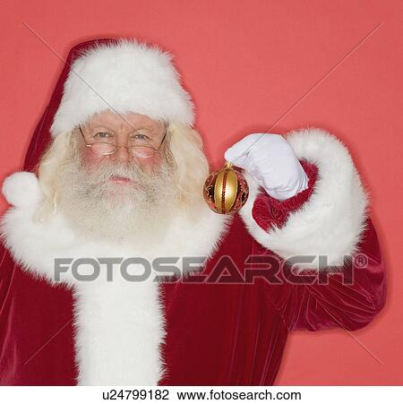 Santa Claus holding Christmas ornament View Large Photo Image Stock Image - Santa Claus holding Christmas ornament. Fotosearch